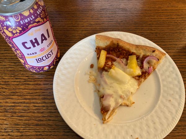 A slice of pizza on a plate accompanied by a can of cider